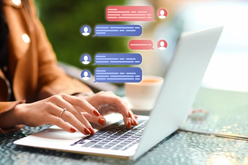 Person typing on a laptop with a blurred background. Illustrated chat bubbles float above the keyboard, suggesting a conversation about branding in digital marketing. A cup is visible in the background.