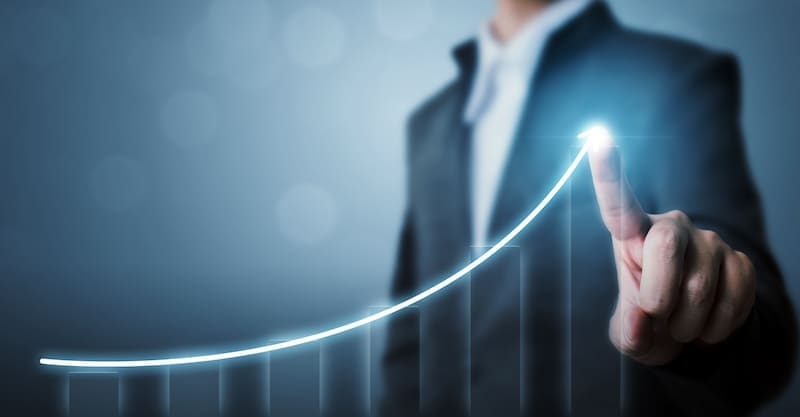 A person in a suit points to the peak of a glowing, upward-trending line graph. The background is blurred, emphasizing the graph that symbolizes growth or success. This visual underscores the importance of corporate reputation management and suggests positive progress in business or data metrics.