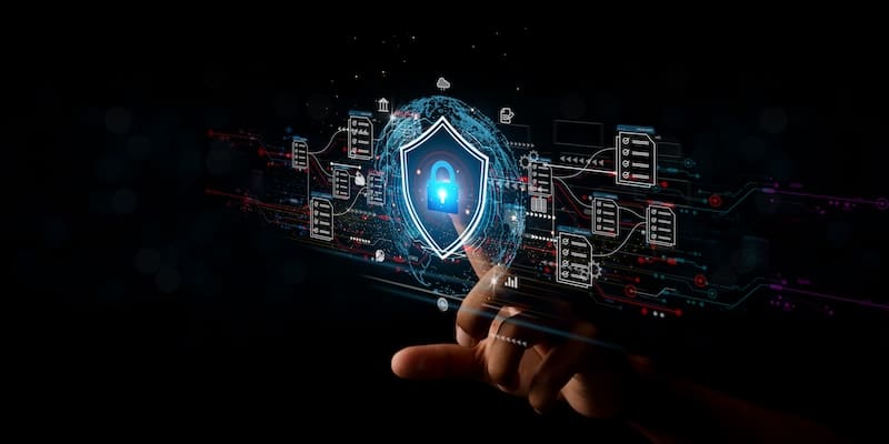 A hand touching a digital interface with a blue shield icon and padlock, symbolizing cybersecurity. The background is dark with various floating digital icons and circuit-like patterns, representing data protection and technological security.