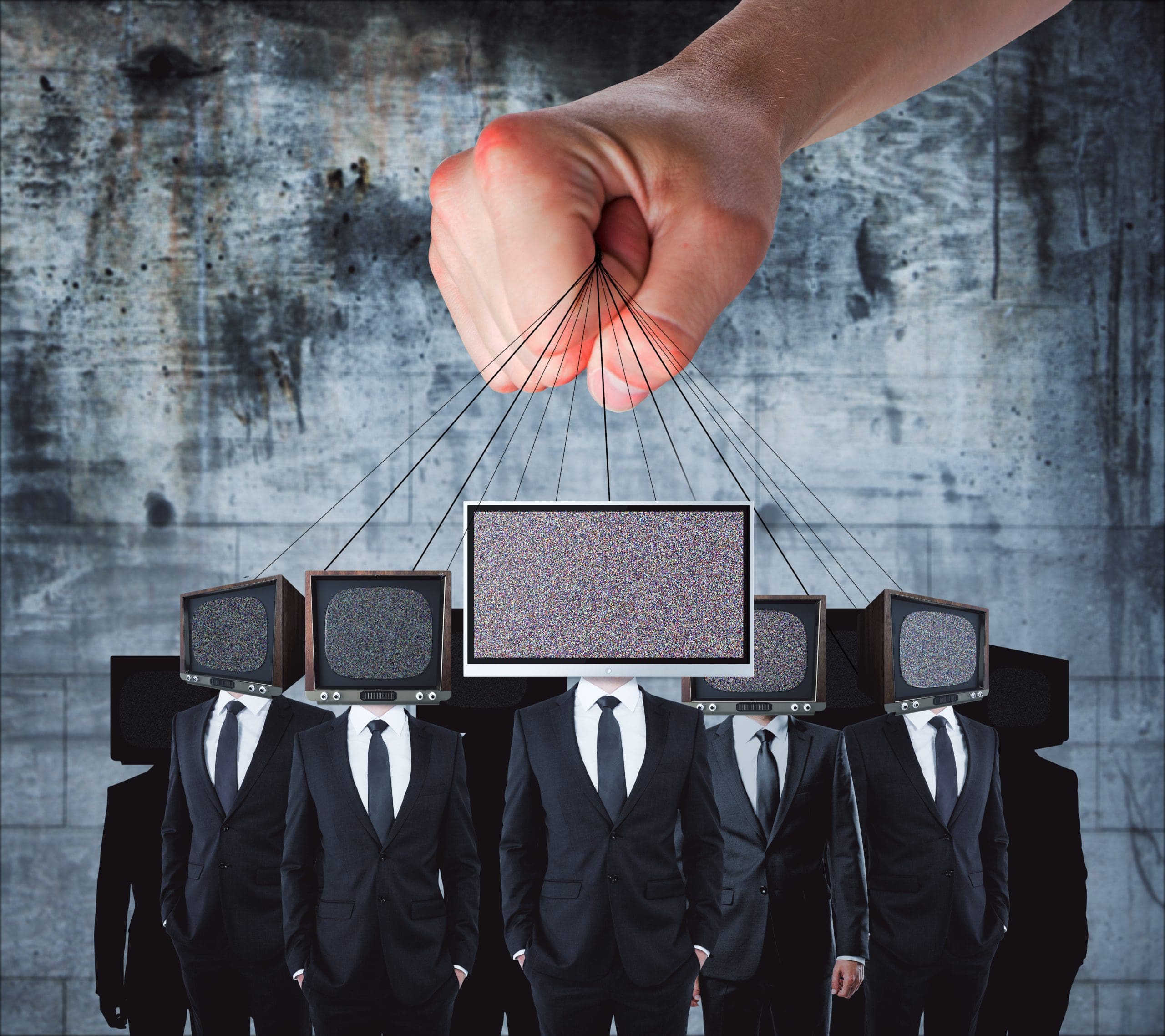 A large hand controls puppets with TV screens for heads, displaying static. The figures, dressed in black suits, stand against a grungy concrete background. The imagery suggests themes of control and media influence.